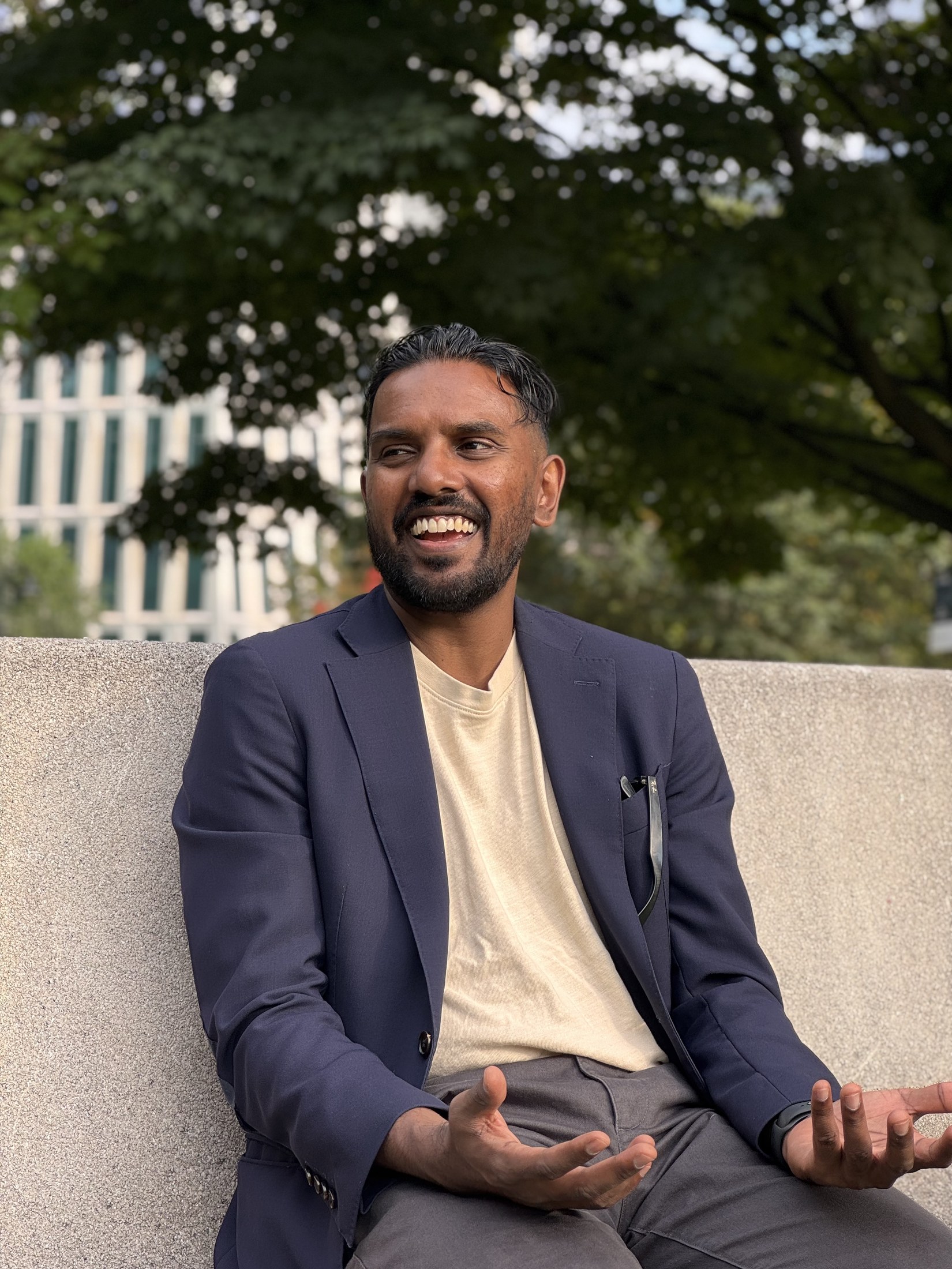 Christopher Balkaran laughing and gesturing during a conversation outdoors