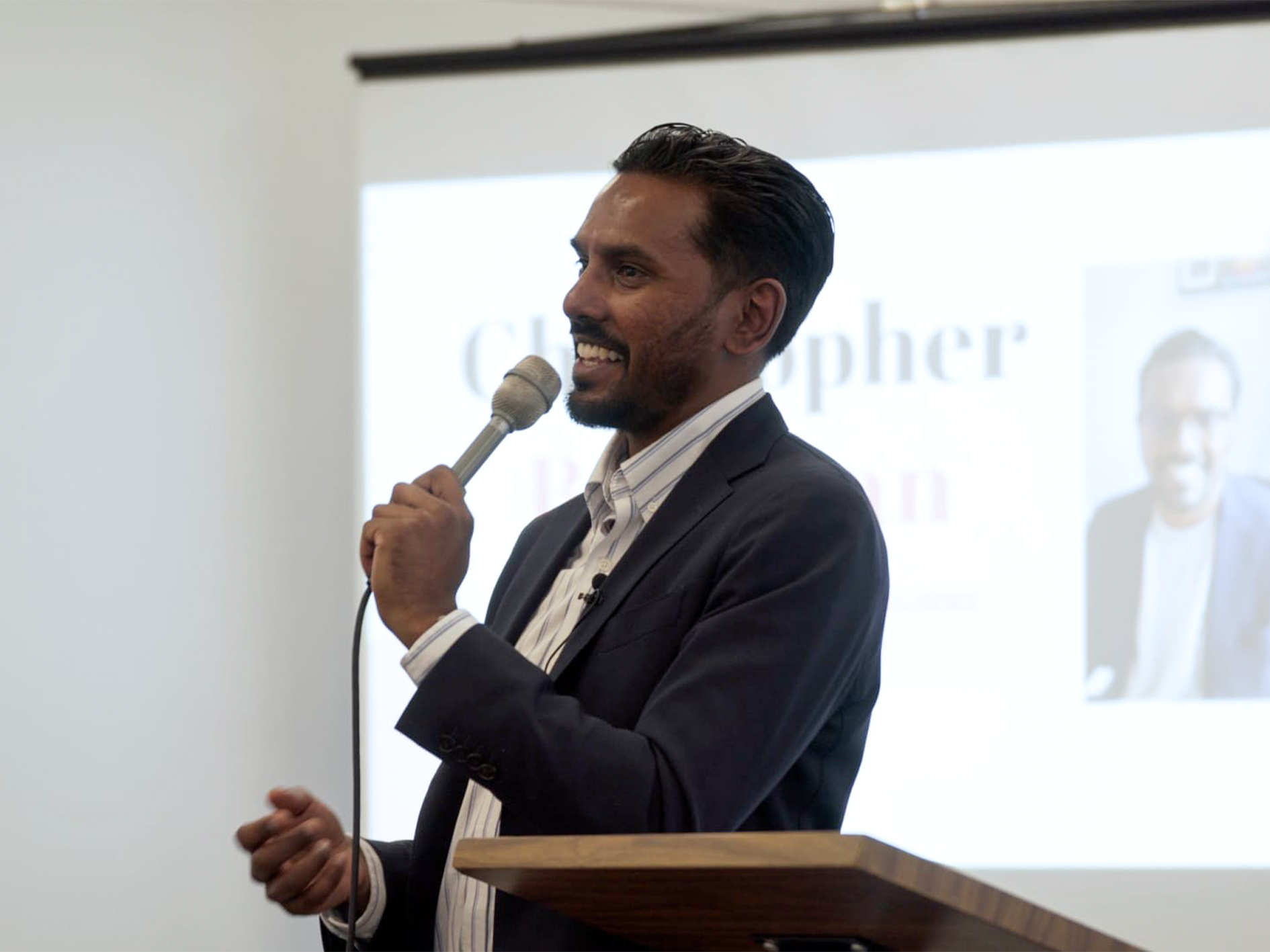 Christopher Balkaran speaking with a microphone during a live event